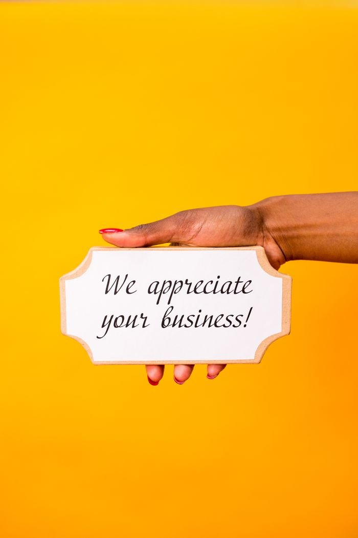 services-01 A hand holding a sign with 'We appreciate your business!' against a yellow background.